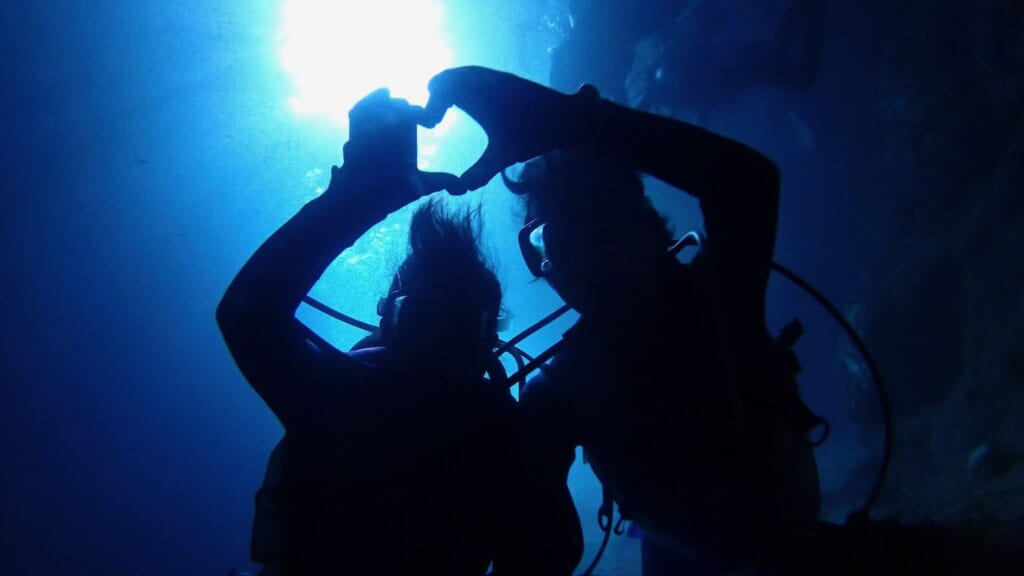 青の洞窟で初心者ダイバーの2人がハートのシルエット写真を撮影している。