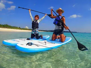 SUPに座って綺麗な海をバックに楽しんでいる家族